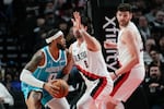 Charlotte Hornets forward Miles Bridges (0) looks to get around Portland Trail Blazers forward Deni Avdija (8) and center Donovan Clingan during the first half of an NBA basketball game Tuesday, March 10, 2026, in Portland, Ore.