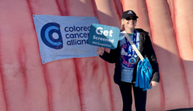 woman holding a sign in front of a pink foam tunnel