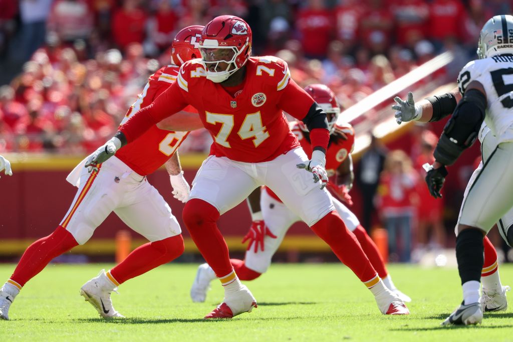Kansas City Chiefs player number 74 in a red jersey and white pants in a crouched stance on a football field.