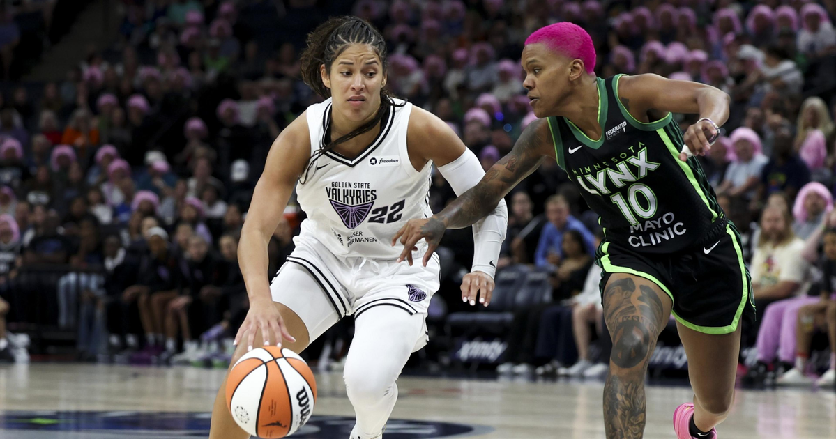 A basketball player in a white Golden State Valkyries uniform dribbles the ball while a Minnesota Lynx player with bright pink hair defends closely.