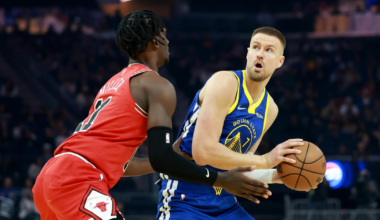 A Golden State Warriors player holds a basketball while being closely guarded by a Chicago Bulls player during a game.