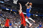 Denver Nuggets guard Bruce Brown, right, drives to the rim as Portland Trail Blazers forward Deni Avdija defends in the second half of an NBA basketball game Sunday, March 22, 2026, in Denver.