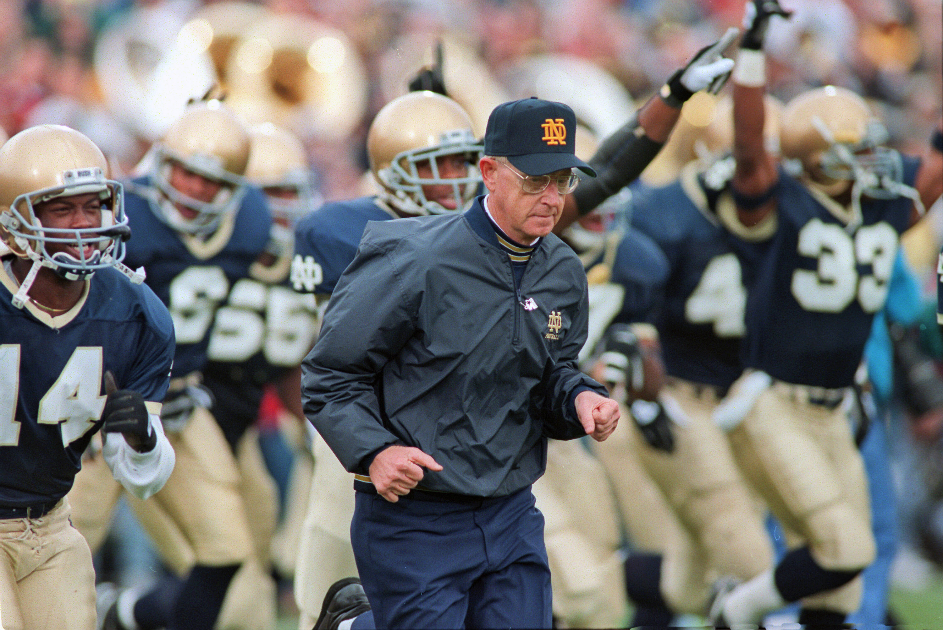 Notre Dame coach Lou Holtz runs onto the field with...