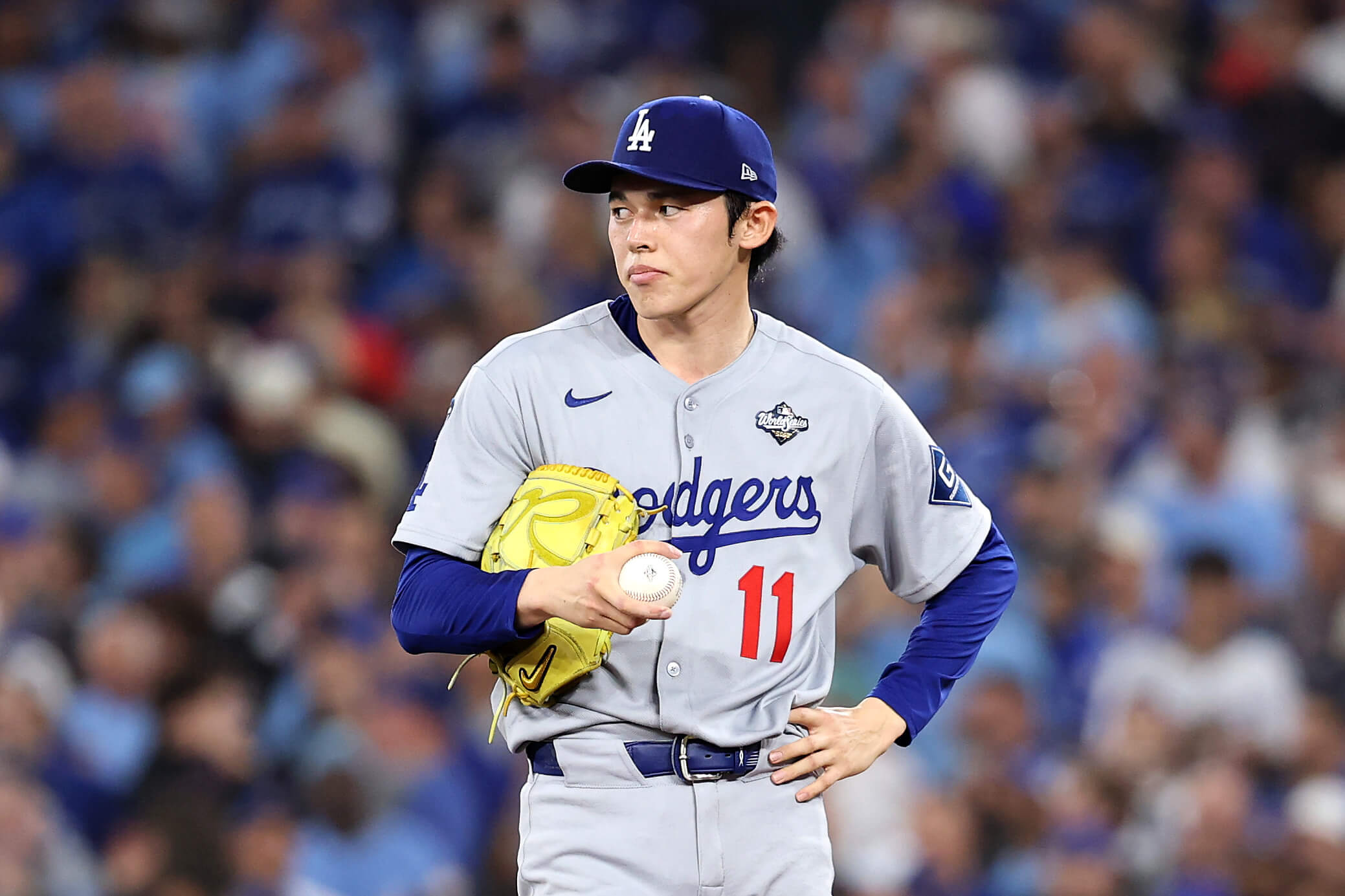 Roki Sasaki of the Los Angeles Dodgers, holding the ball in his right hand and with his glove tucked against his torso by his right elbow, reacts in Game 6 of the 2025 World Series.