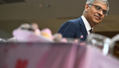 Image of a pink tablecloth with a man in a suit standing behind the table.