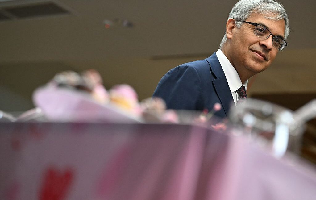 Image of a pink tablecloth with a man in a suit standing behind the table.