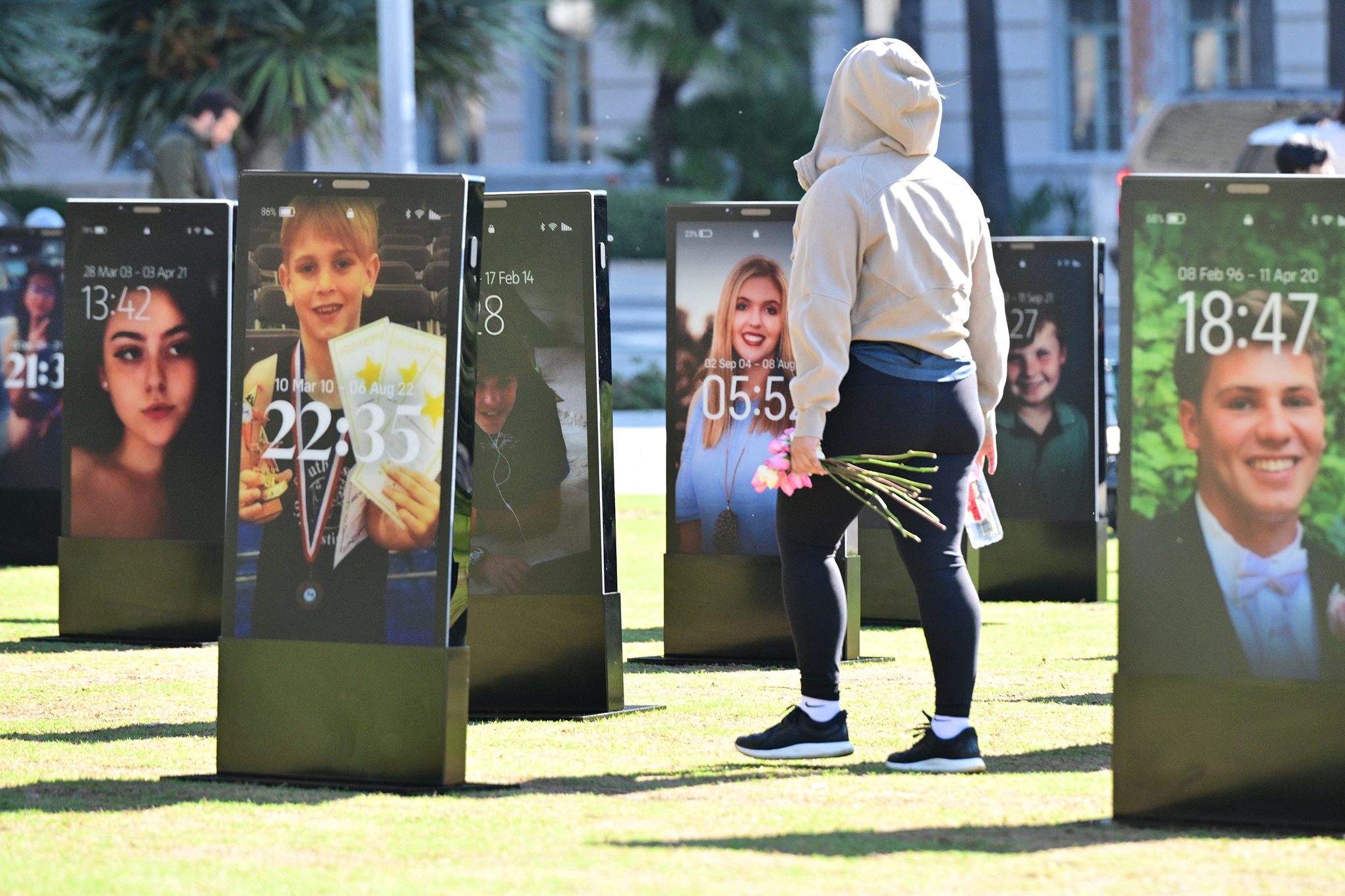 A figure walks through an art installation of giant 3D phones featuring deceased children.