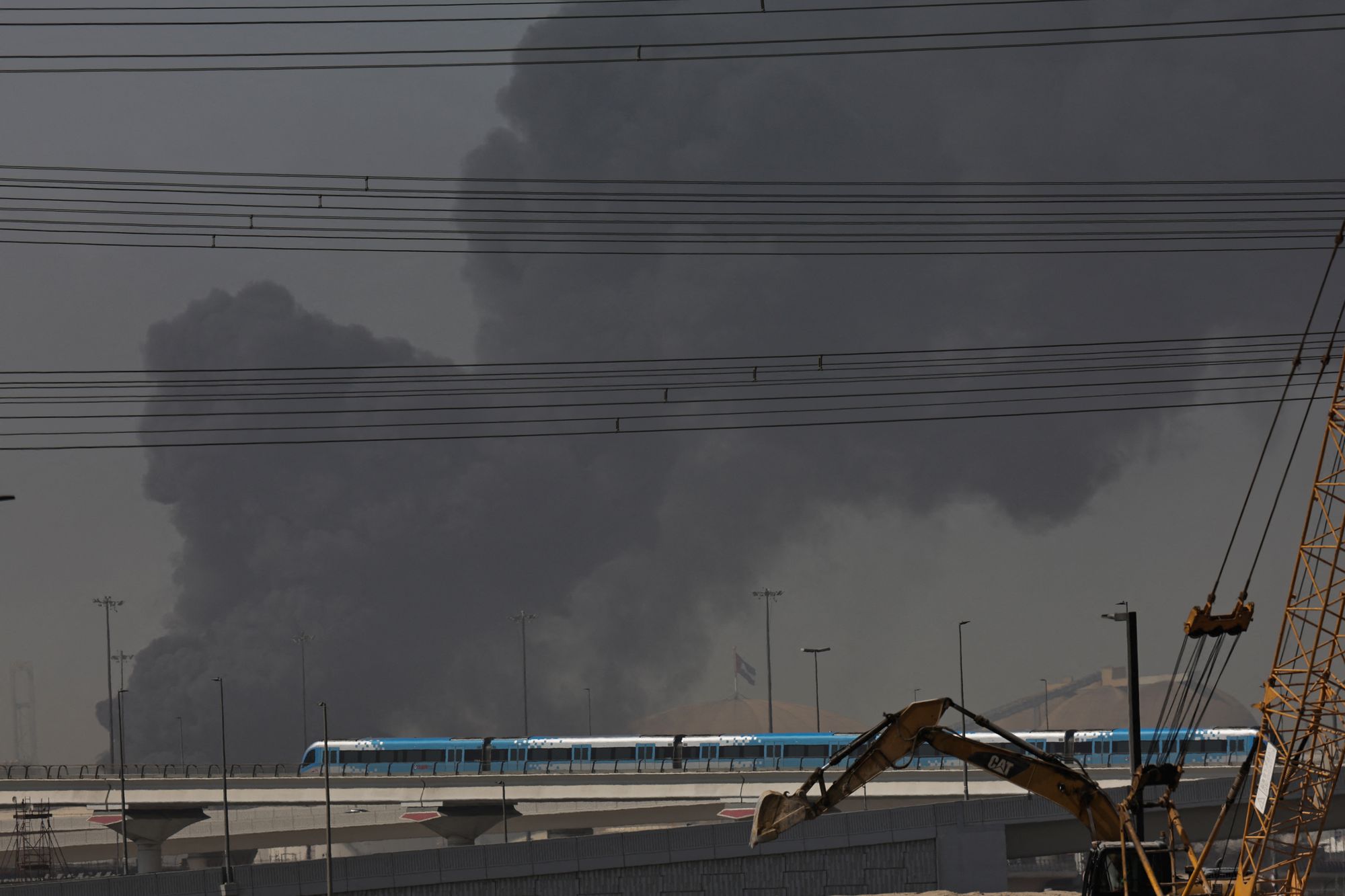 File: A metro train passes by a plume of smoke rising from the port of Jebel Ali following a reported Iranian strike in Dubai on March 1, 2026
