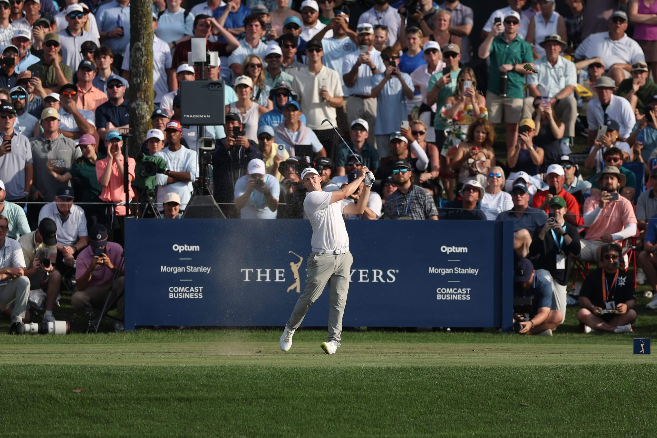 Matt Fitzpatrick, with the gallery behind him, follows through on his swing after teeing off on the par-3 17th.