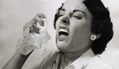 Picture shows a woman about to sneeze holding a handkerchief in her hand.