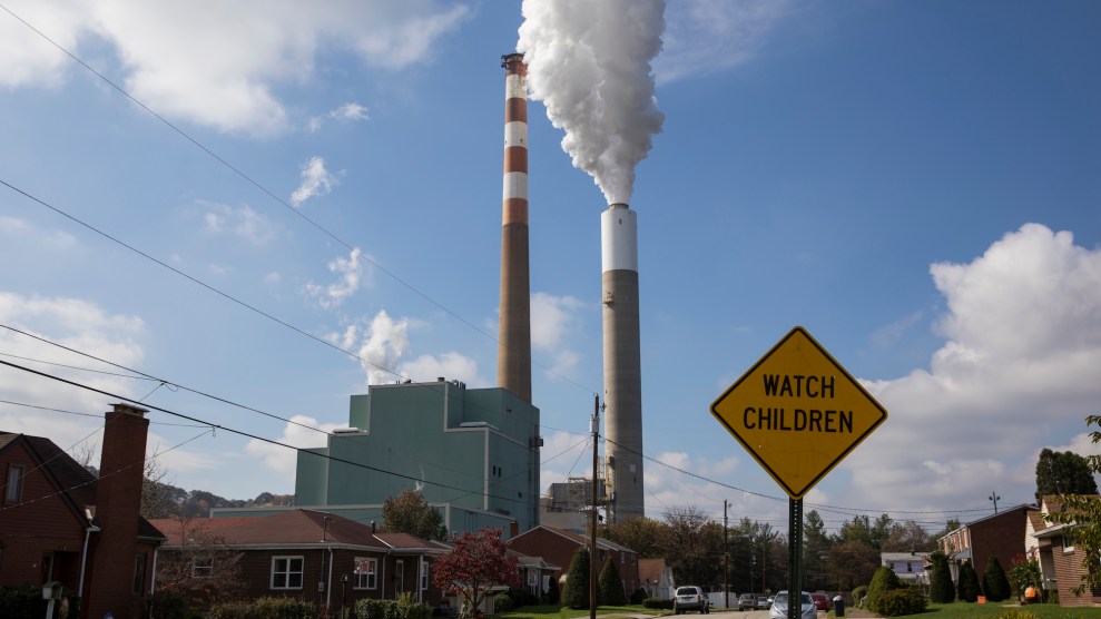 Two smoke stacks stand over a suburban street of single-story brick houses. A road sign says "Watch Children"