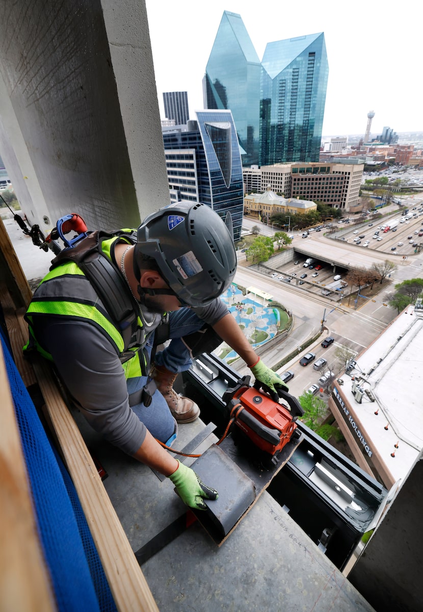 Looking out the window frame on the 16th floor, construction worker David Ramirez lines up...