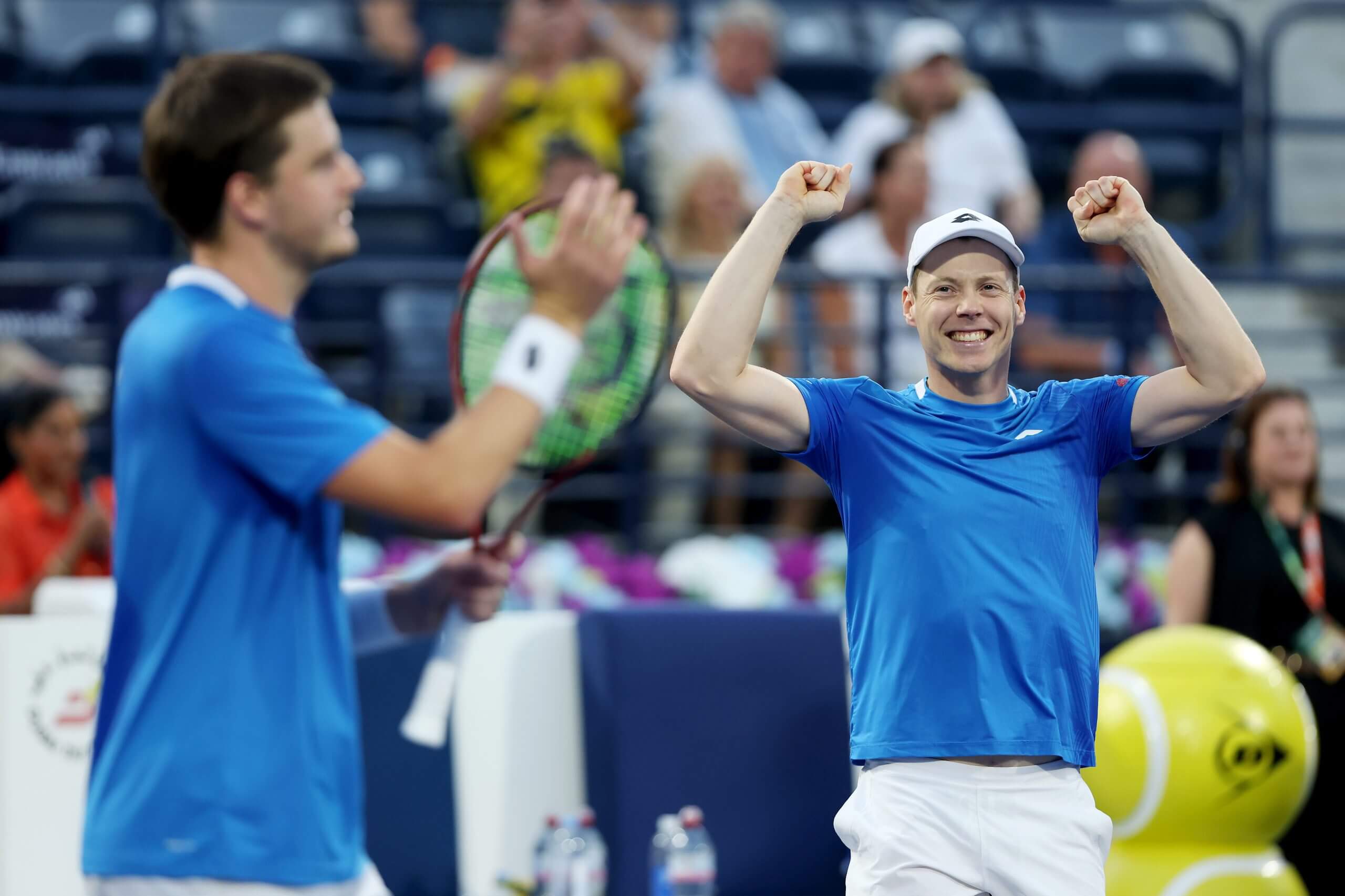 Harri Heliövaara (right) celebrates victory with partner Henry Patten (left) by raising his hands in the air as Patten claps his tennis racket.