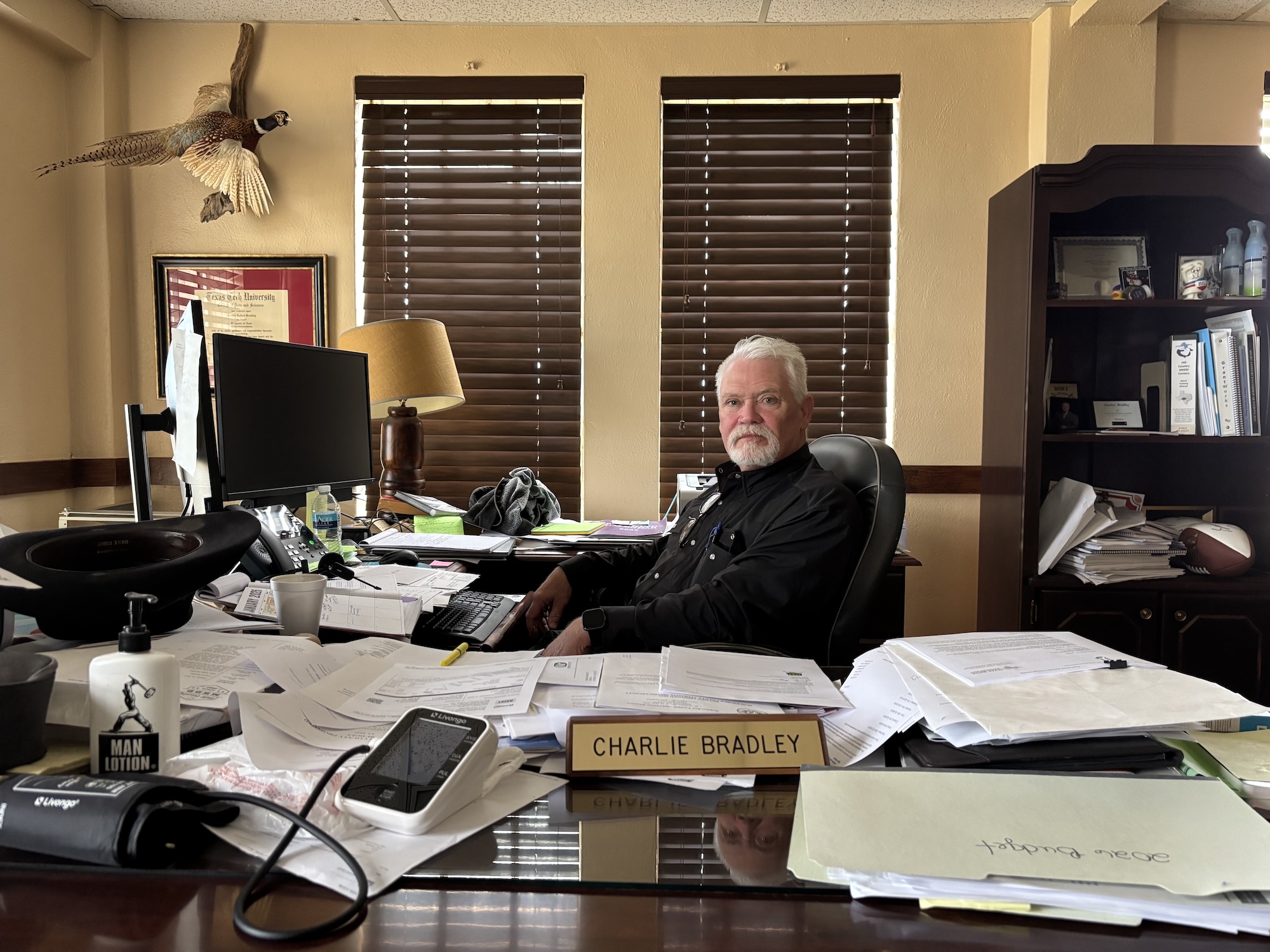 A man sits behind a desk with nameplate for Charlie Bradley
