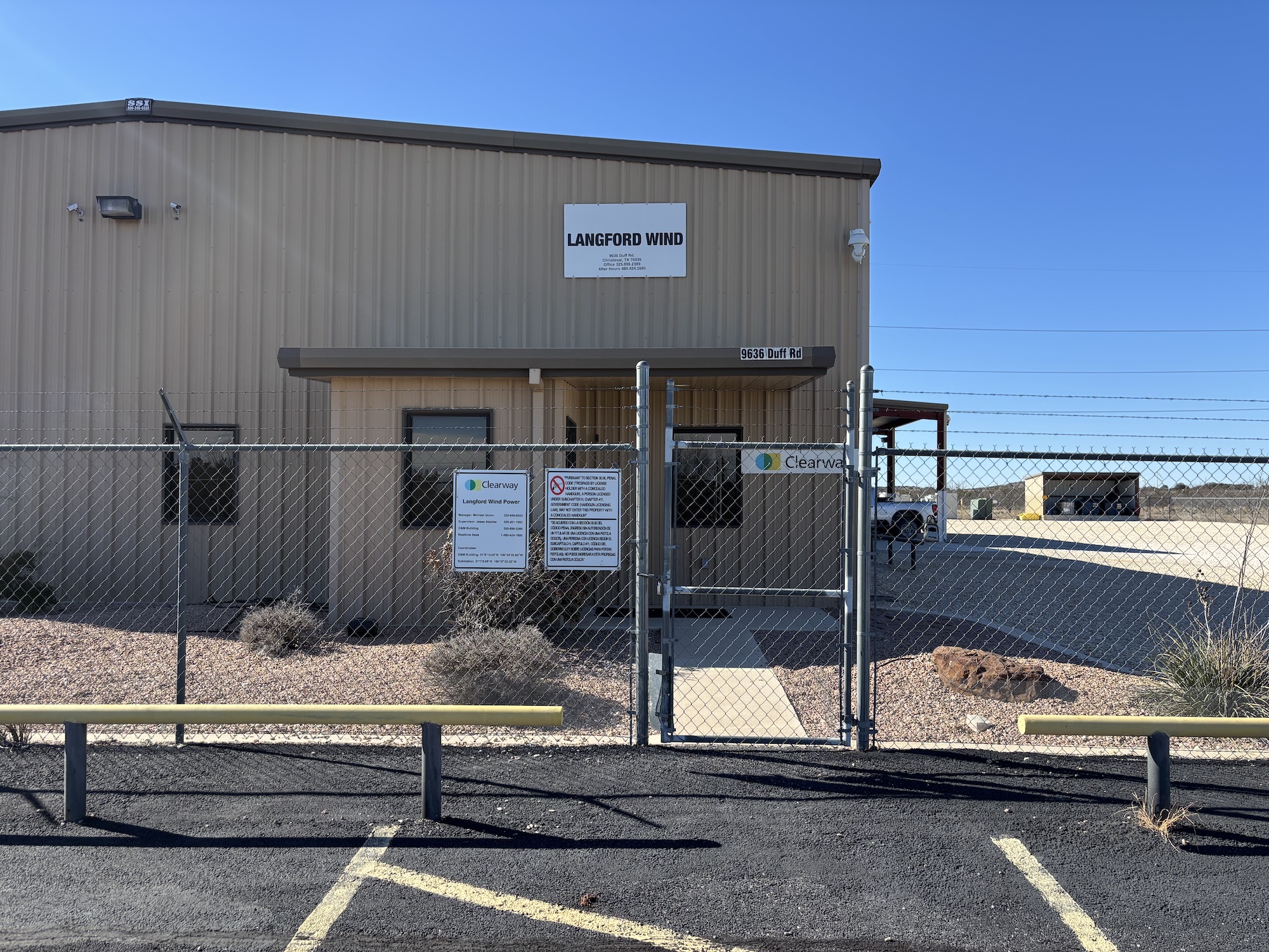 A building with a sign for langford wind beyond a wire fence