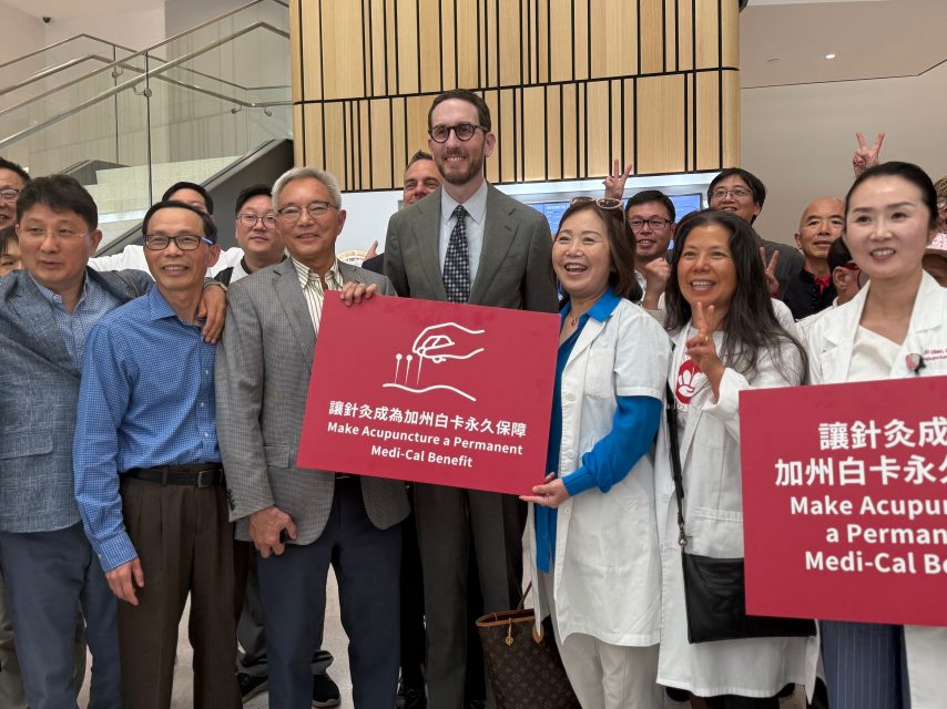 A group of people, including doctors and officials, hold signs promoting permanent acupuncture coverage as a Medi-Cal benefit.
