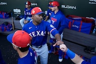 Texas Rangers pitcher Kumar Rocker fist bumps teammates before a spring training game...