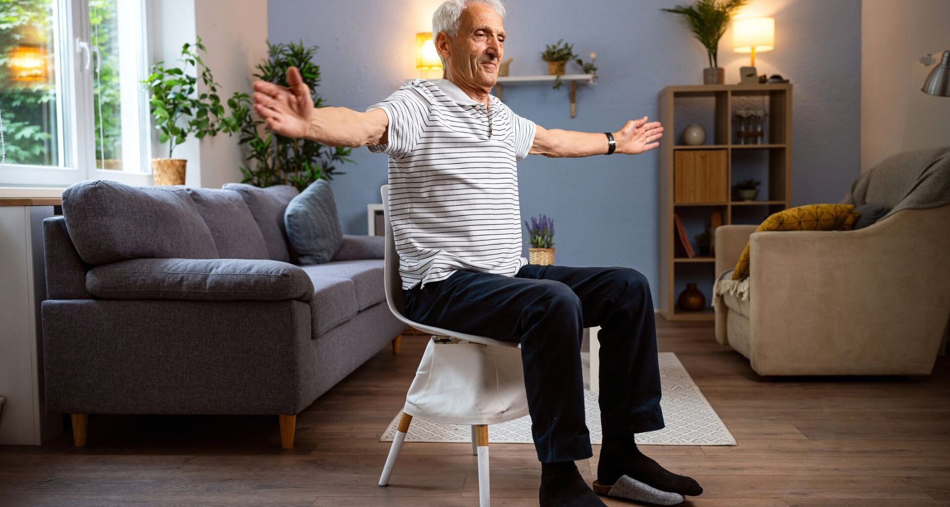 man sits on chair mid exercise with arms extended out