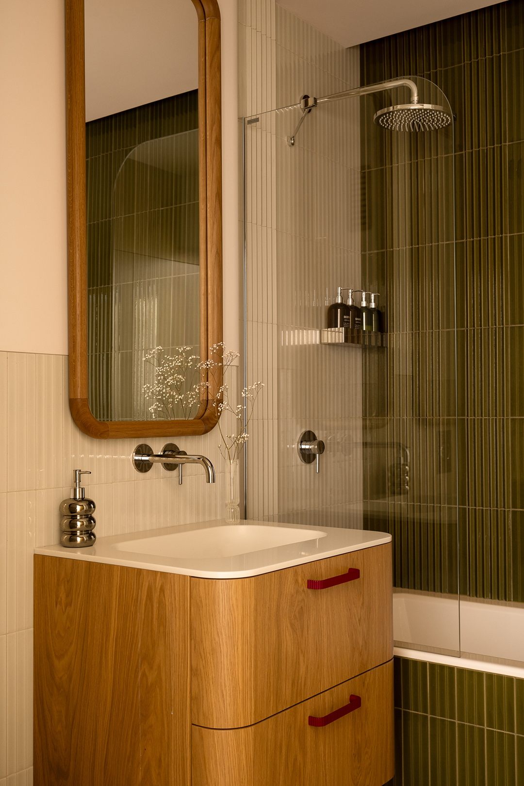 bathroom with wood sink, wood mirror, and green tiled shower
