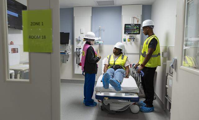 From left to right: Jackson Memorial Hospital registered nurse Belkis Diaz, Miami Dade College student Amyra Gowon and Emergency Medical Technician Edward Laden perform a simulation of a patient's experience in a patient room during a tour of the hospital's new emergency department on Thursday, March 5, 2026, in Miami, Fla. The new facility doubles the size of the current emergency room and is expected to reduce patient wait times.