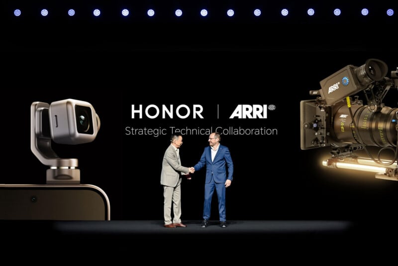 Two men in suits shake hands on stage in front of large displays of an HONOR camera and an ARRI cinema camera, with the text “HONOR ARRI Strategic Technical Collaboration” behind them.