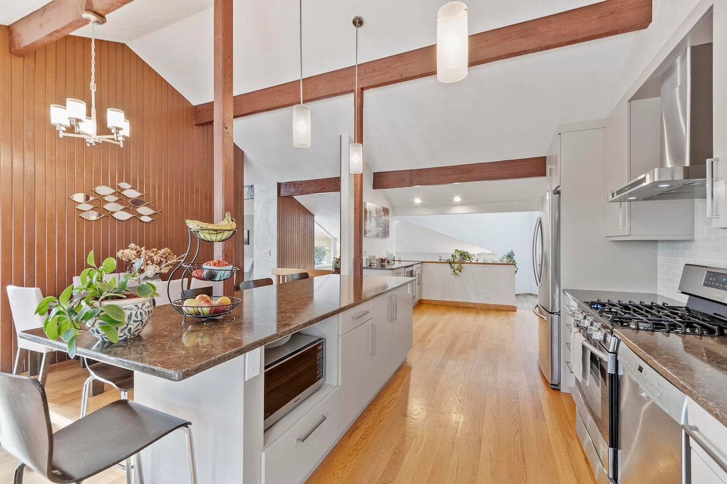 The kitchen has a long island with white cabinetry, a granite countertop, and overhangs on two sides.