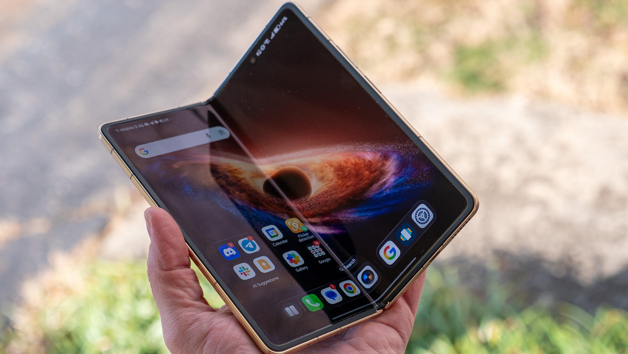 Holding the gold Honor Magic V6 while the screen is partially folded