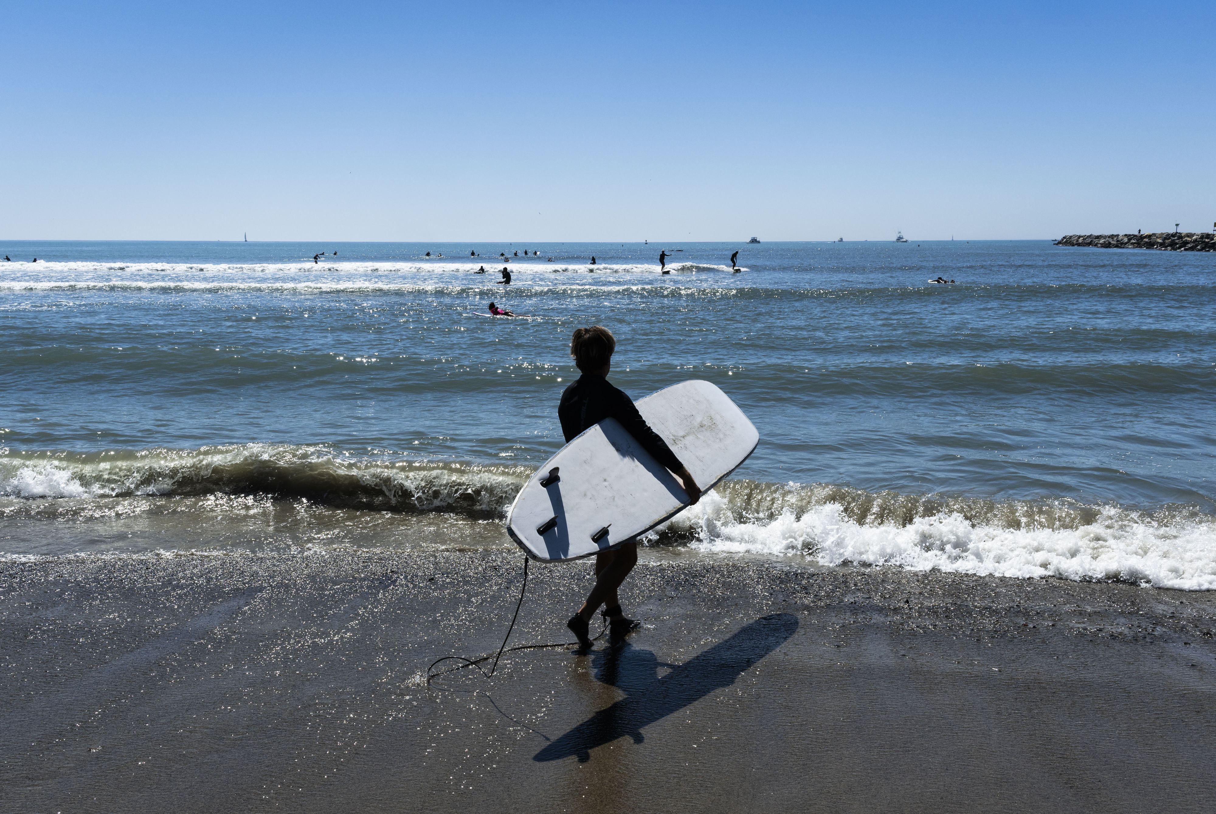 A surfer heads to the waves at Doheny State Beach...