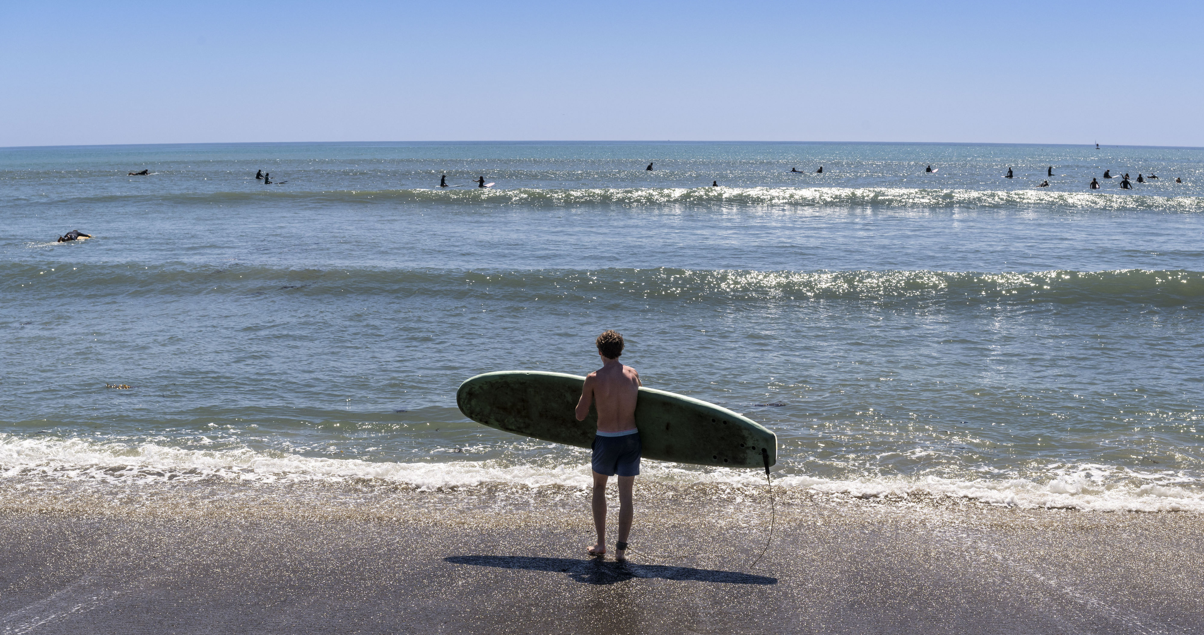 A surfer heads to the waves at Doheny State Beach...