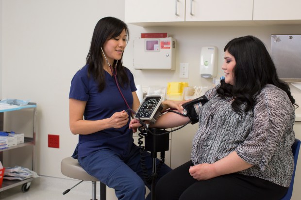 Above, a patient has her blood pressure taken at a health clinic run by Anaheim-based Planned Parenthood of Orange and San Bernardino counties, which announced Monday, Oct. 13, 2025, that it is laying off 81 people as it shutters Melody Health, its primary care practice.