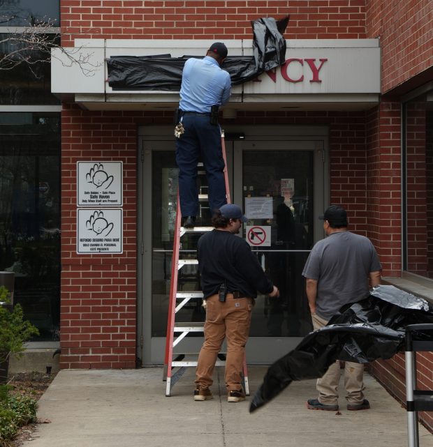 Workers cover an Emergency sign at West Suburban Medical Center in Oak Park on March 26, 2026. (Cam'ron Hardy/Pioneer Press)