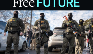 Immigration agents dressed up as soldiers with big guns facing the camera with cars and sky behind them