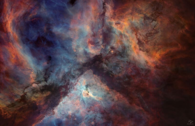Colorful, swirling clouds of interstellar gas and dust in space, with blue, orange, and red hues blending together, creating an ethereal, abstract nebula formation.