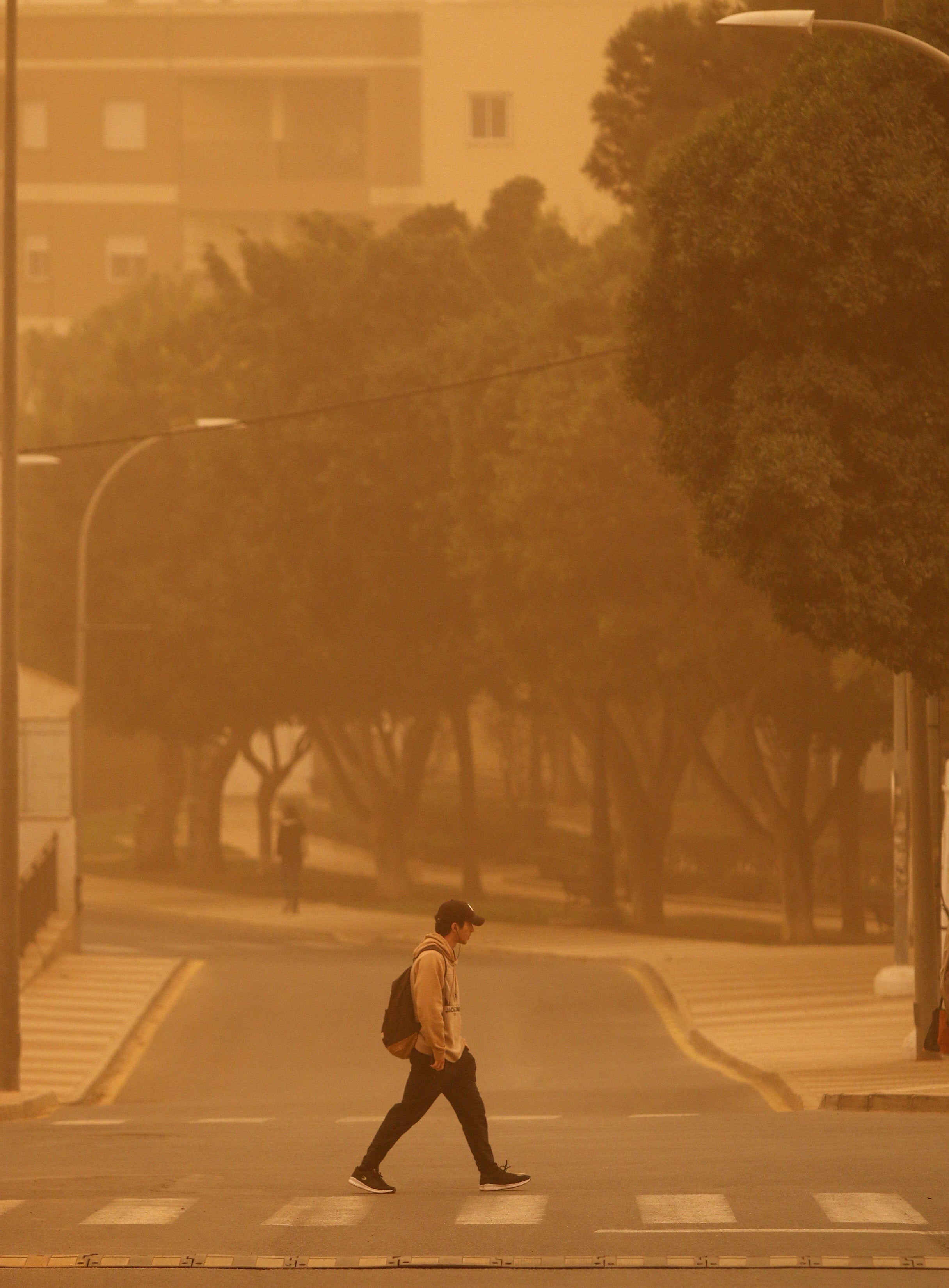 A man crosses a road as dust from the Sahara desert blankets the coastal city of Roquetas de Mar, Spain, 15 March 2022. A wave of airborne dust from the Sahara moved through southern and central Spain propelled by storm Celia.