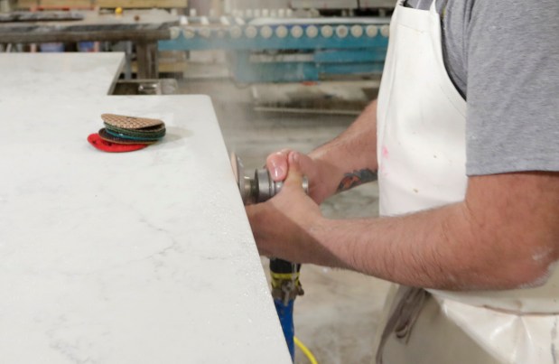 A worker polishes the edge of a kitchen countertop cut from quartz slabs in the production facility in 2019. (AP Photo/Michael Conroy)
