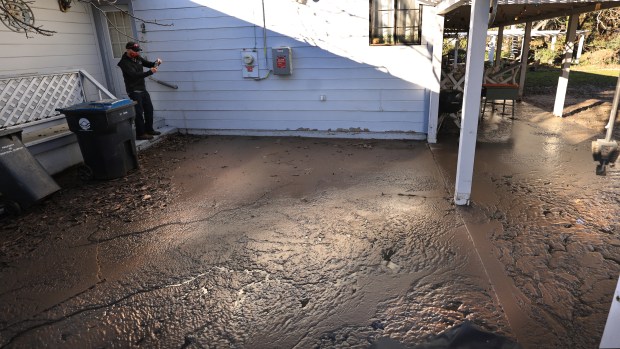 Mike Holland documents the amount of mud and sewage which rushed in to a neighbors yard on Ro9ben Lane in the Burns Valley neighborhood of Clearlake on Robin Lane, Tuesday, Jan. 13, 2026. (Kent Porter / The Press Democrat)