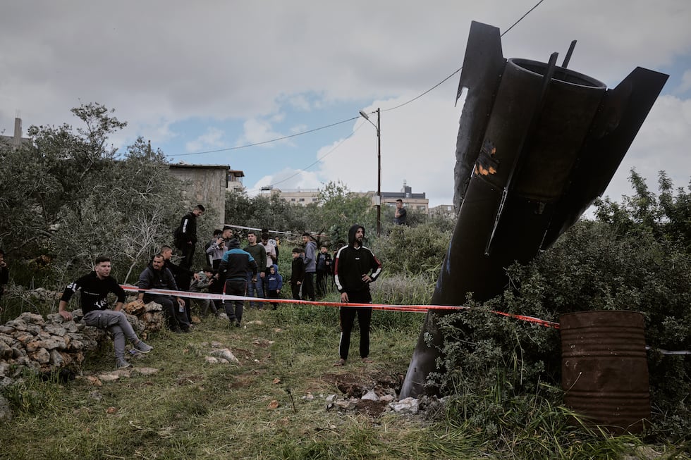 Palestinians gather around the wreckage of an Iranian missile that landed in the West Bank...