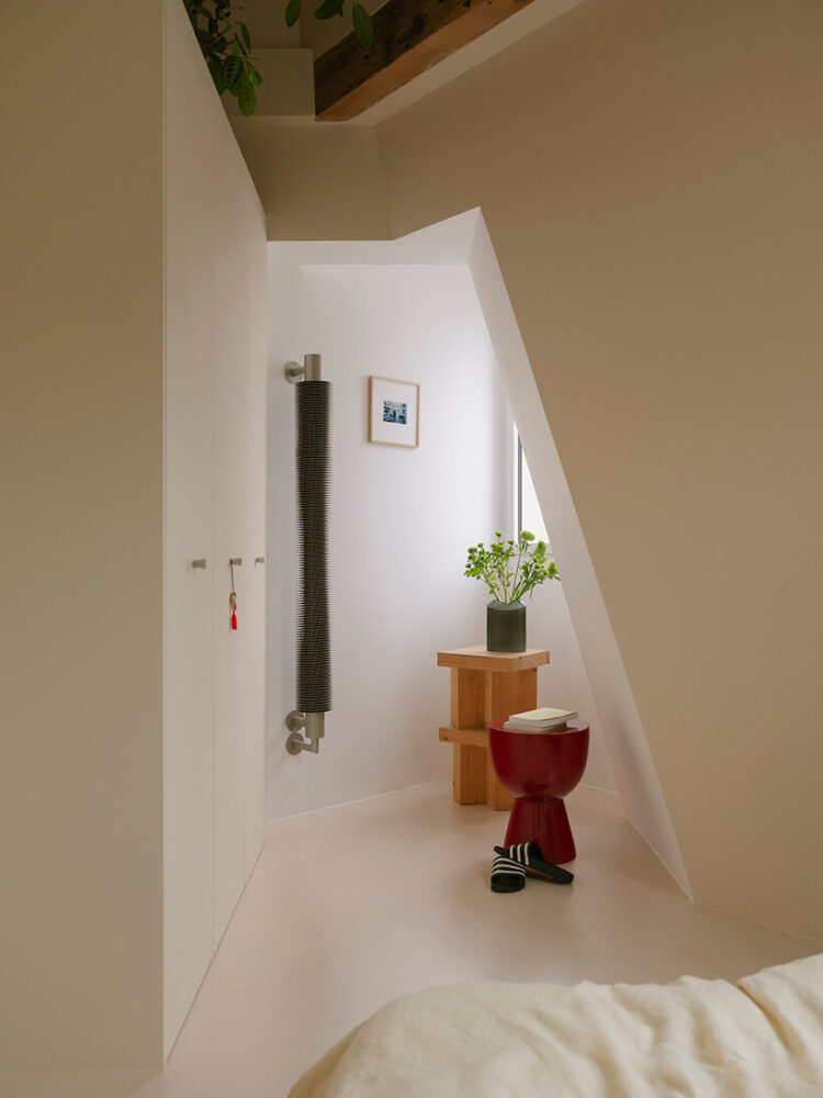 a compact nook beneath the roofline becomes a small dressing and reading corner