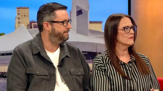 Lee draper wearing a white top and grey jacket, Helen wearing a striped black and white blouse. Both are wearing glasses.