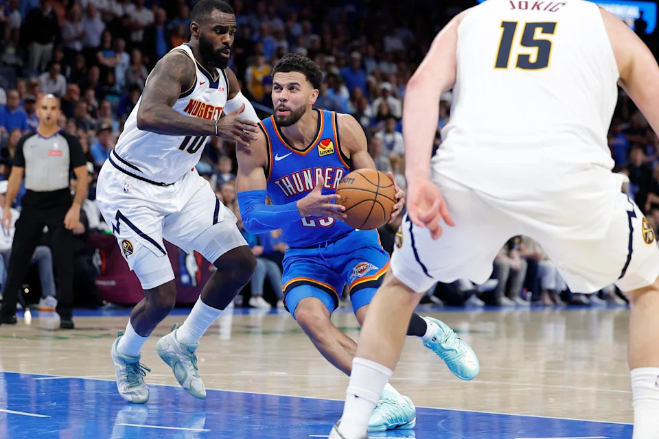 Mar 9, 2026; Oklahoma City, Oklahoma, USA; Oklahoma City Thunder guard Ajay Mitchell (25) drives between Denver Nuggets guard/forward Tim Hardaway Jr. (10) and center Nikola Jokić (15) during the second half at Paycom Center. Mandatory Credit: Alonzo Adams-Imagn Images