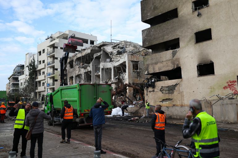 TOPSHOT - People look at a building damaged in a reported overnight Iranian strike in Tel Aviv on March 1, 2026.