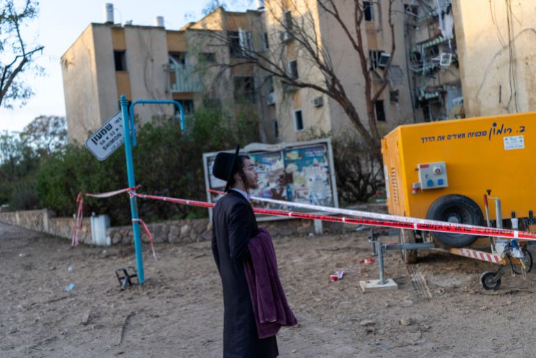 An Israeli Orthodox Jew inspects the site of an Iranian missile strike in Arad on March 22, 2026.