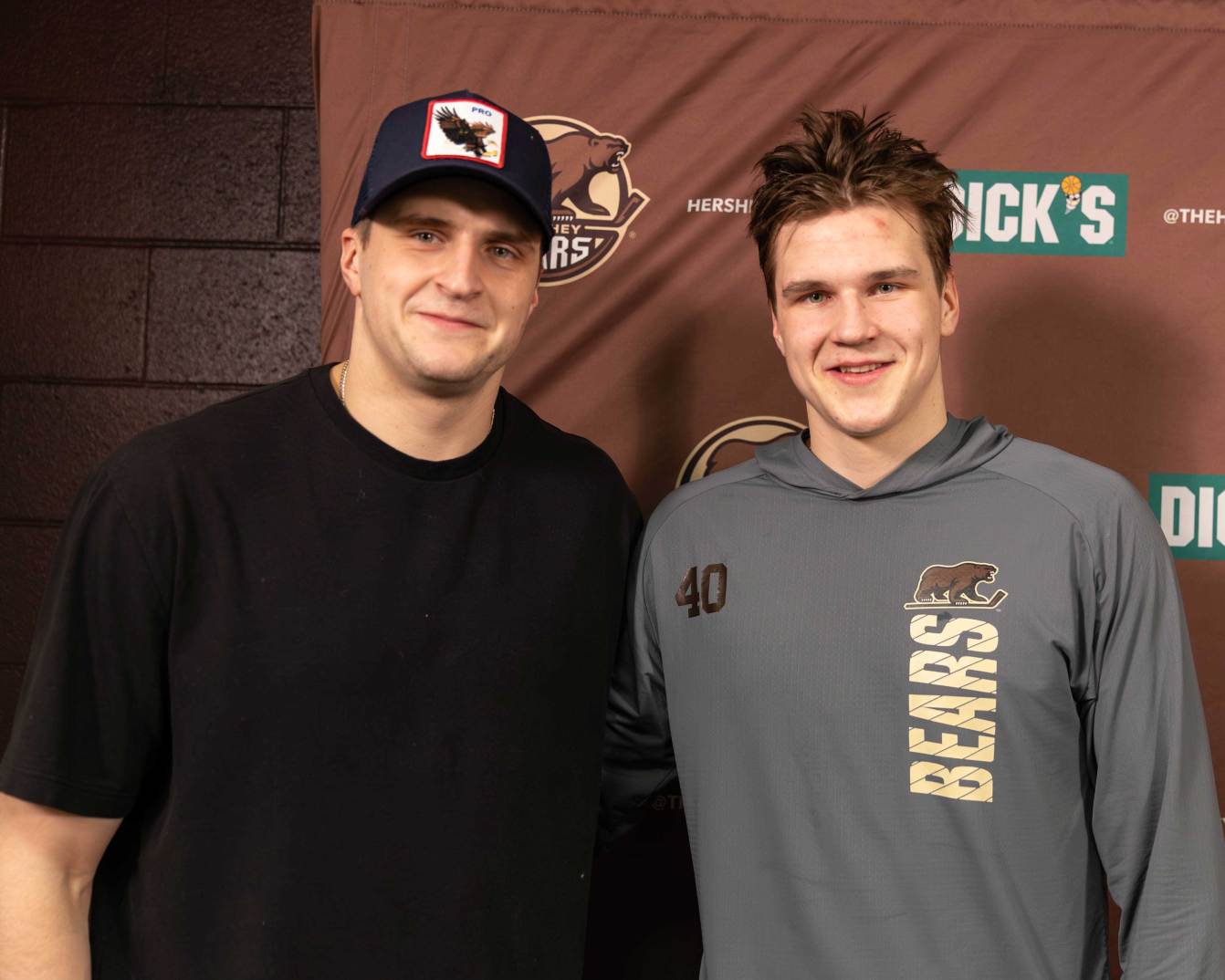 Aliaksei Protas and Ilya Protas pose together in the Hershey Bears' media room