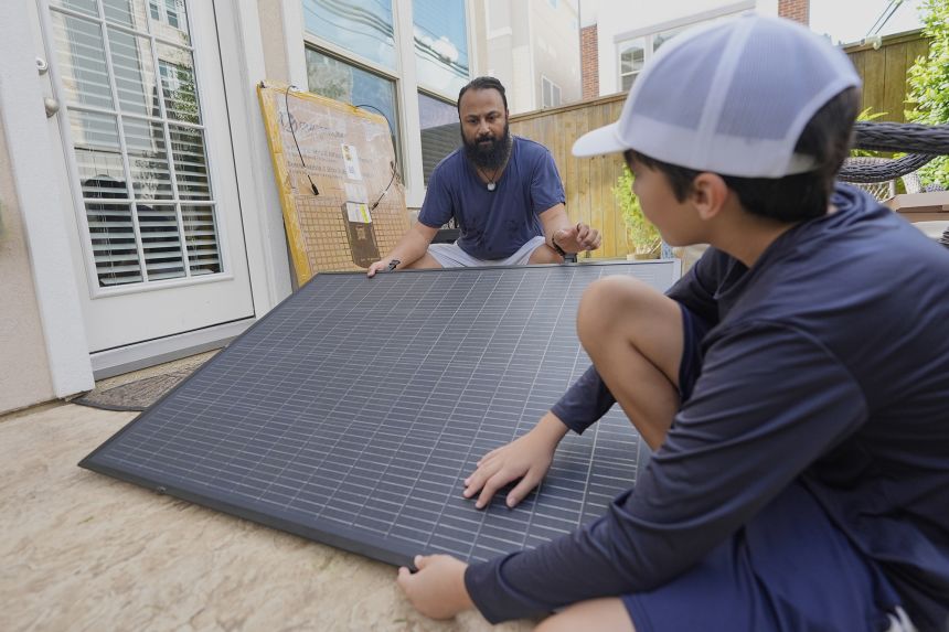 Bhavin Misra, left, and his son, Rumi, 10, attach a solar panel while assembling a Craftstrom Solar plug-in kit at their home Tuesday, Aug. 5, 2025, in Houston.