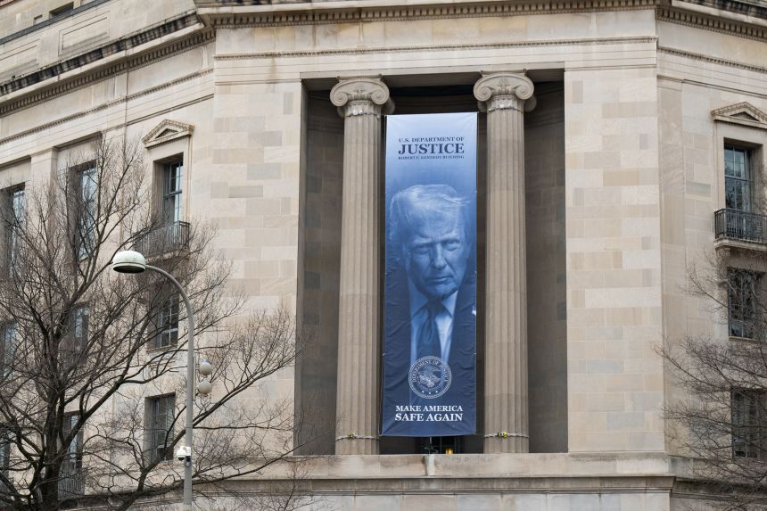 A banner of President Trump hangs from the Department of Justice building in Washington, DC on February 23, 2026.