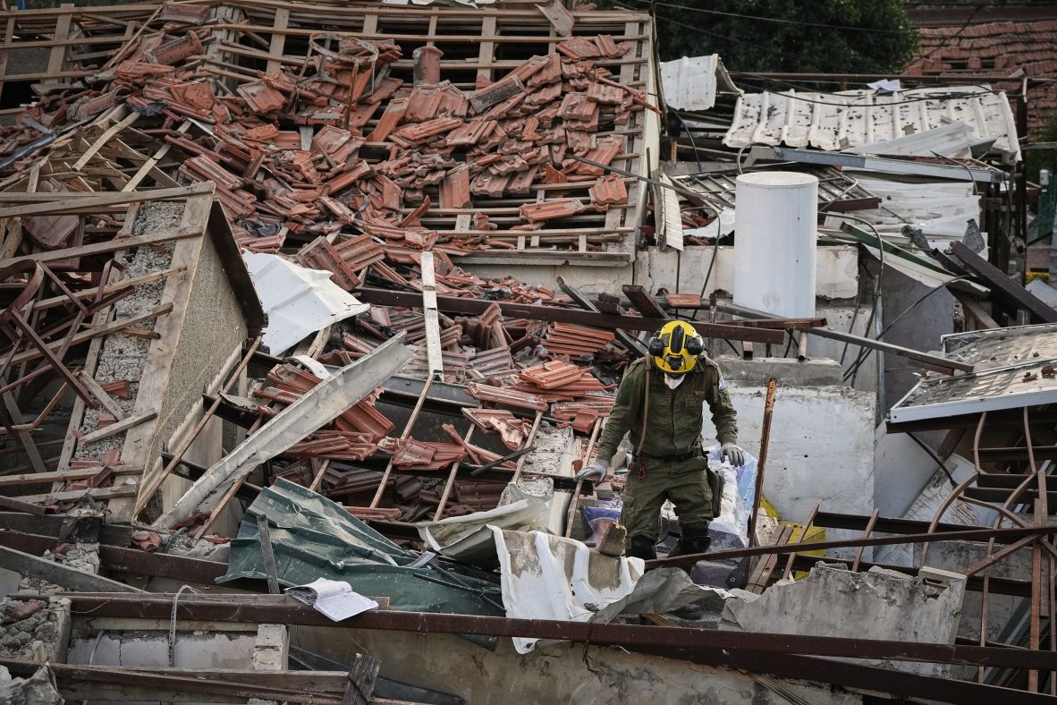 An officer from Israel's Home Front Command searches through the rubble of a destroyed house after it was struck by a missile in Beit Shemesh.