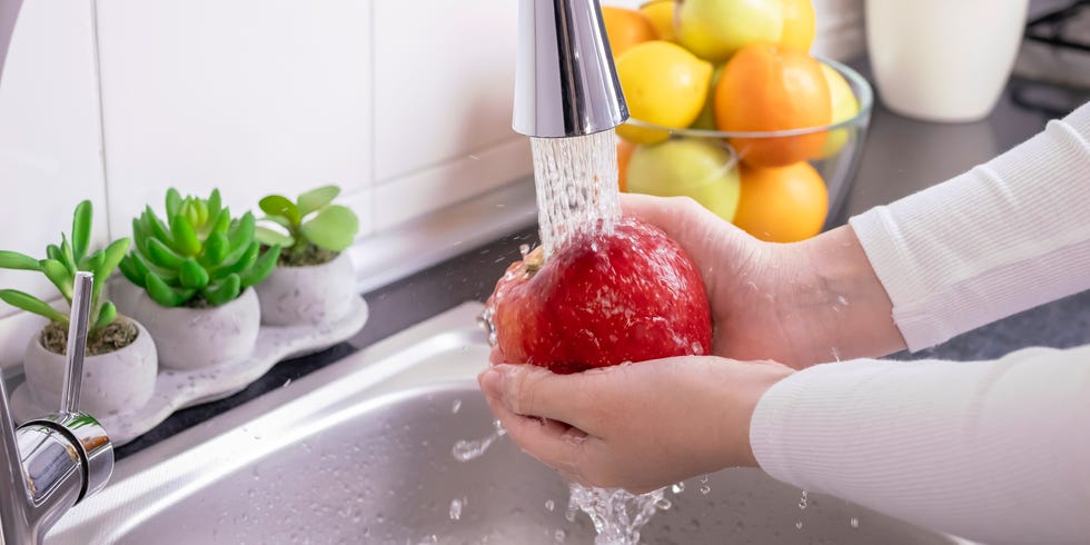 Woman hands washing fresh red apple in the kitchen