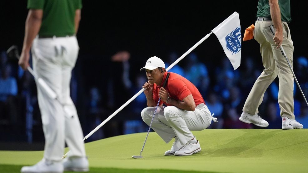 Tiger Woods helps Jupiter Links Golf Club teammate Tom Kim, not pictured, line up a putt during a match of the TMRW Golf League (TGL) against Boston Common Golf, Monday, Jan. 27, 2025, in Palm Beach Gardens, Fla. (AP Photo/Rebecca Blackwell)