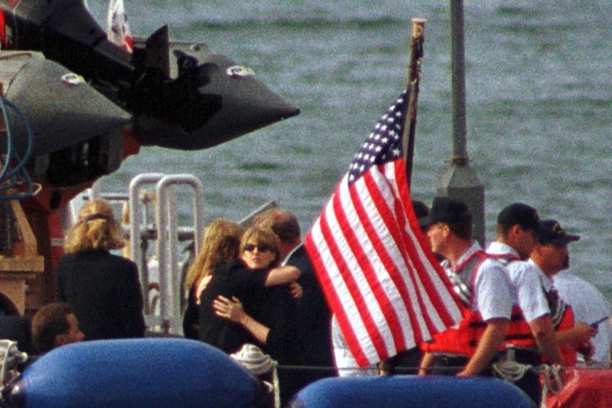 Members of the Kennedy and Bessette families embrace at the stern of the Coast Guard ship Sanibel as they prepare to travel to the USS Briscoe on July 22, 1999, for the burial at sea of John F. Kennedy Jr., Carolyn Bessette Kennedy and Lauren Bessette.