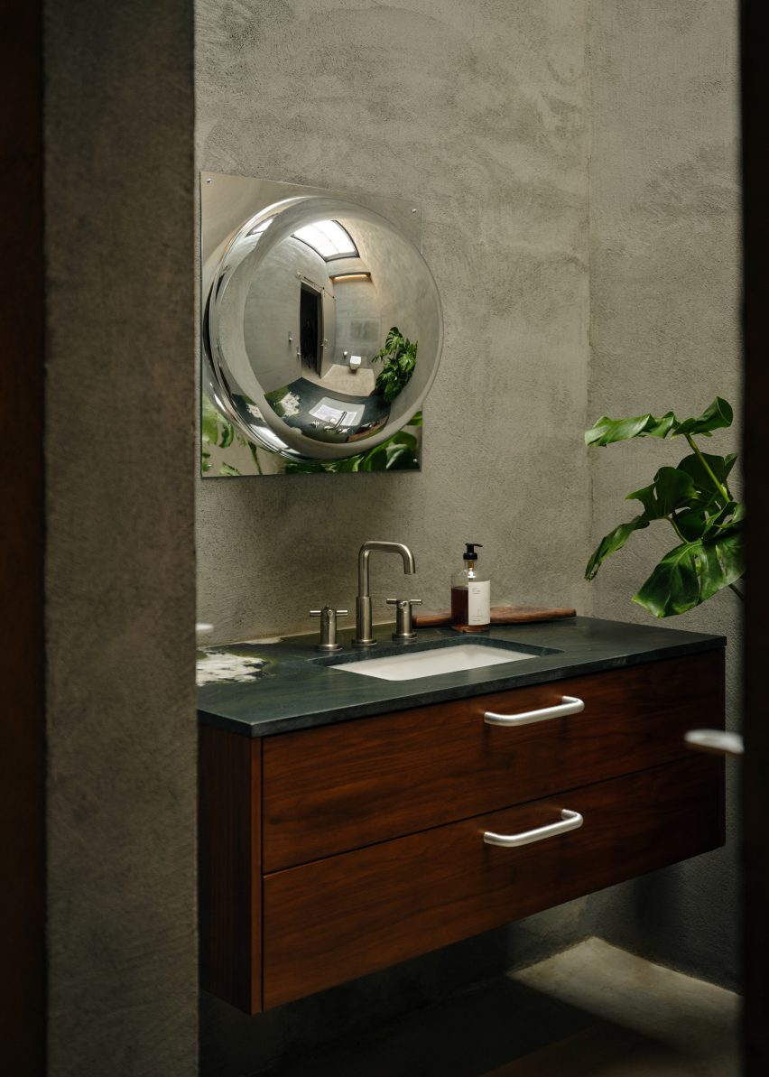 Bathroom with a dark green stone vanity counter and a convex mirror
